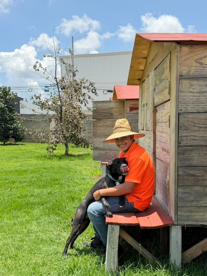 Cuidador cargando a un perrito junto a una casita
